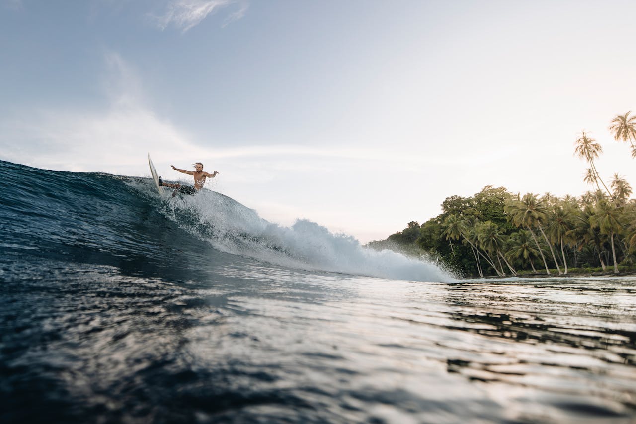 Home Surfer riding a big wave near tropical beach in Indonesia during a sunny day.